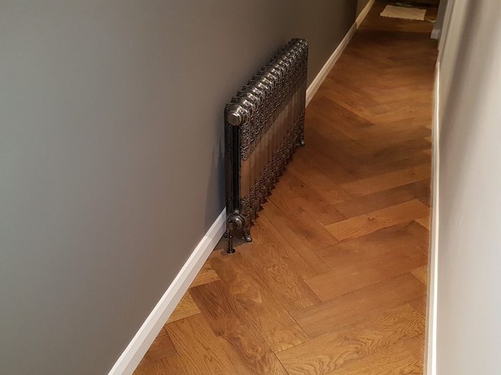 Finished hallway with dark radiator, timber floor and painted walls
